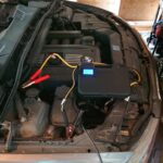 DIY car coding power supply connected to a car battery, showing voltage display