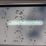 Close-up of a Vehicle Identification Number (VIN) sticker on a car windshield, highlighting its importance for vehicle identification and history checks.