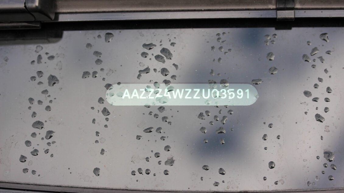 Close-up of a Vehicle Identification Number (VIN) sticker on a car windshield, highlighting its importance for vehicle identification and history checks.