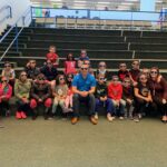 A group of kids, a teacher, and Jonathan sitting on steps all wearing Bluehost sunglasses.