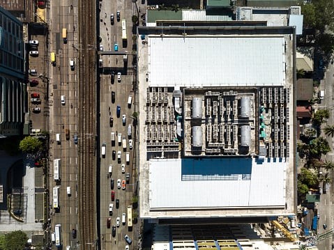 Top view of the roof deck of an office building, with installed VRF HVACs and water storage tanks. A large avenue with a rail system installed in the center lane