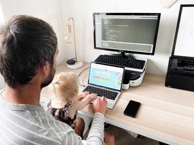 Steven looking at code on a laptop with his daughter Kitty on his lap, representing balancing family and career change.